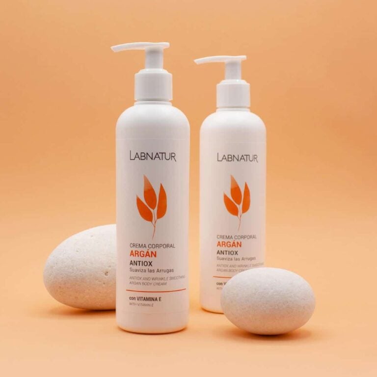 Dos envases de Crema Corporal Argán 400ml Labnatur entre dos piedras claras sobre fondo naranja