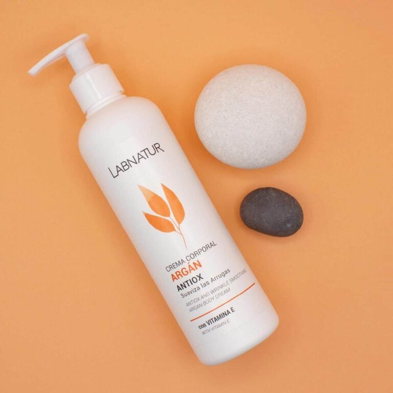 Envase inclinado de Crema Corporal Argán 400ml Labnatur junto a una piedra clara y otra oscura