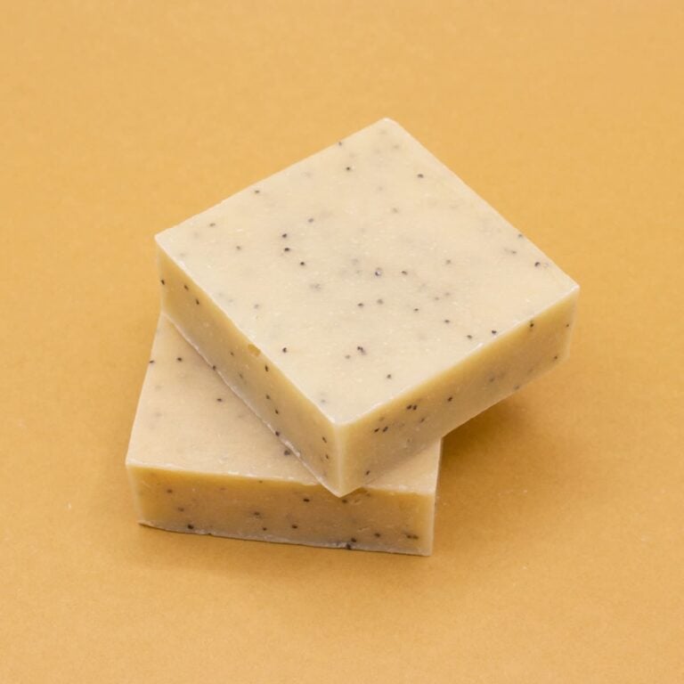 Dos pastillas de Jabón Natural Artesano Leche de Burra 100g Labnatur con semillas de amapola apiladas sobre fondo dorado