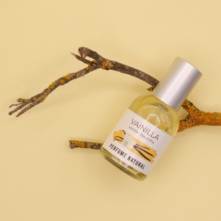 Frasco inclinado de Perfume Vainilla 50ml Labnatur entre ramas con líquenes amarillos y anaranjados