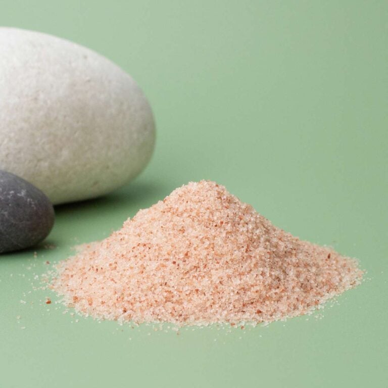 Primer plano de cristales rosados de Sales de Baño del Himalaya Labnatur apilados junto a piedras decorativas