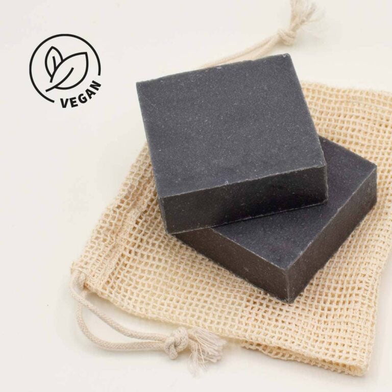 Dos pastillas de Jabón Natural Artesano Carbón Activado 100g Labnatur apiladas sobre una bolsa de malla con sello vegano