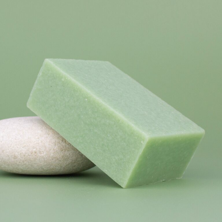 Pastilla verde de Jabón Natural CBD Labnatur 100g apoyada sobre piedra en fondo verde.