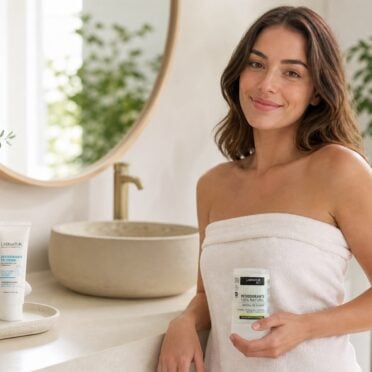 Mujer en un baño luminoso con desodorantes naturales Labnatur, desodorante en crema y desodorante de alumbre.